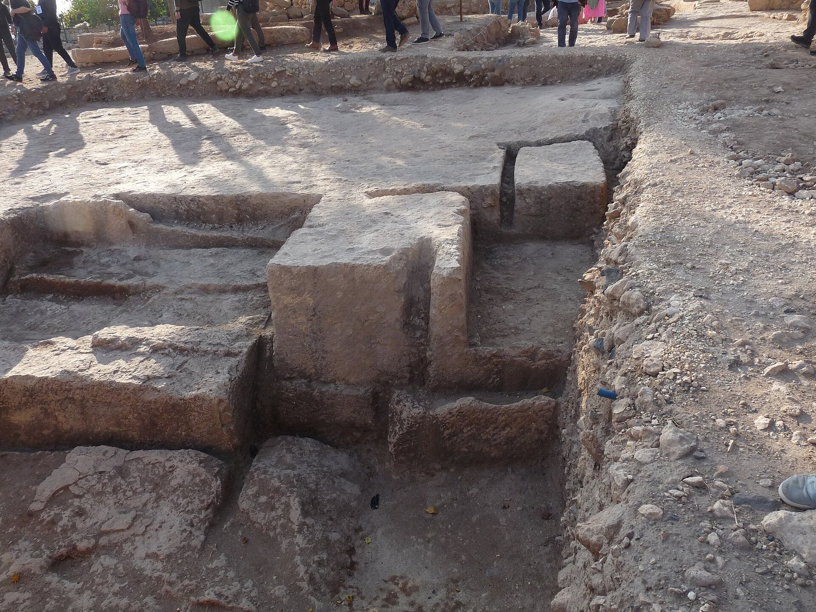 Excavated bedrock-carved architecture at Sayburç with visitors walking above the trench