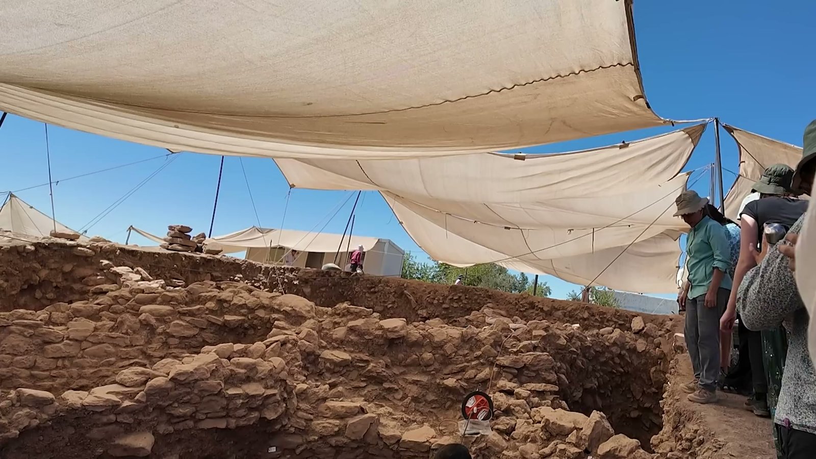 The Sayburç excavation under summer shade cloths, team members working along the trench