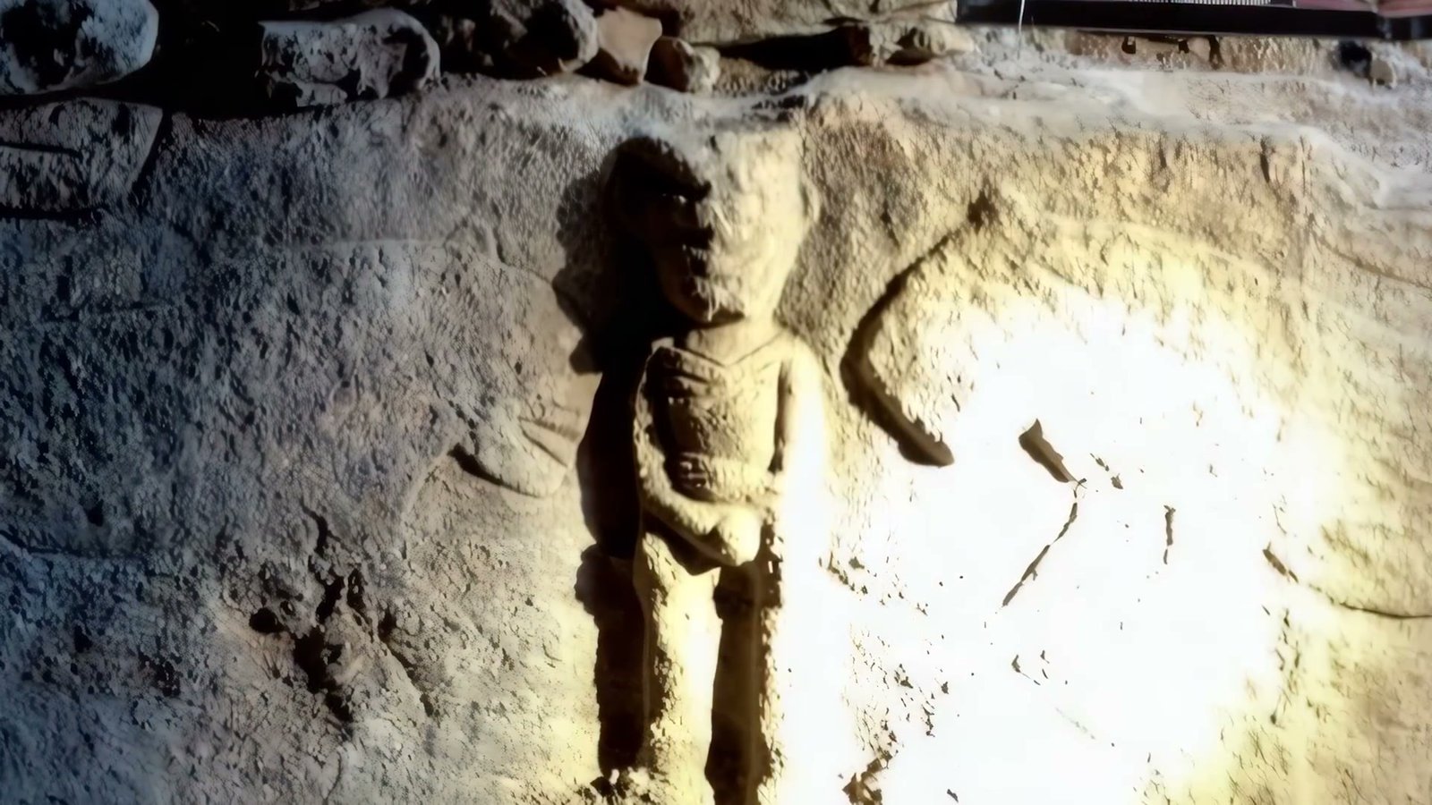 A carved human figure at Sayburç, hands meeting at the chest above a collar at the throat